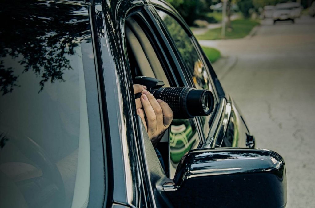image of a car and lens of a camera protruding out of the window